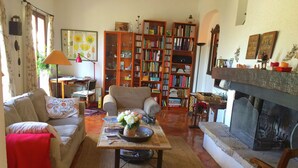 A cozy living room with a fireplace, a bookshelf, and a dining area. - Verdon Views: Pool & Terrace (Montagnac Montpézat)