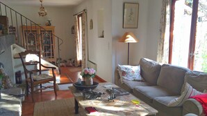 A living room with a sofa, a coffee table, a chair, a lamp, and a staircase leading to another room. - Verdon Views: Pool & Terrace (Montagnac Montpézat)