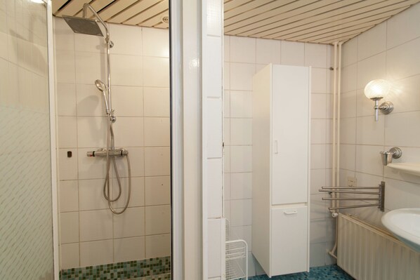 A bathroom with a shower, a toilet, a sink, and a towel rack.