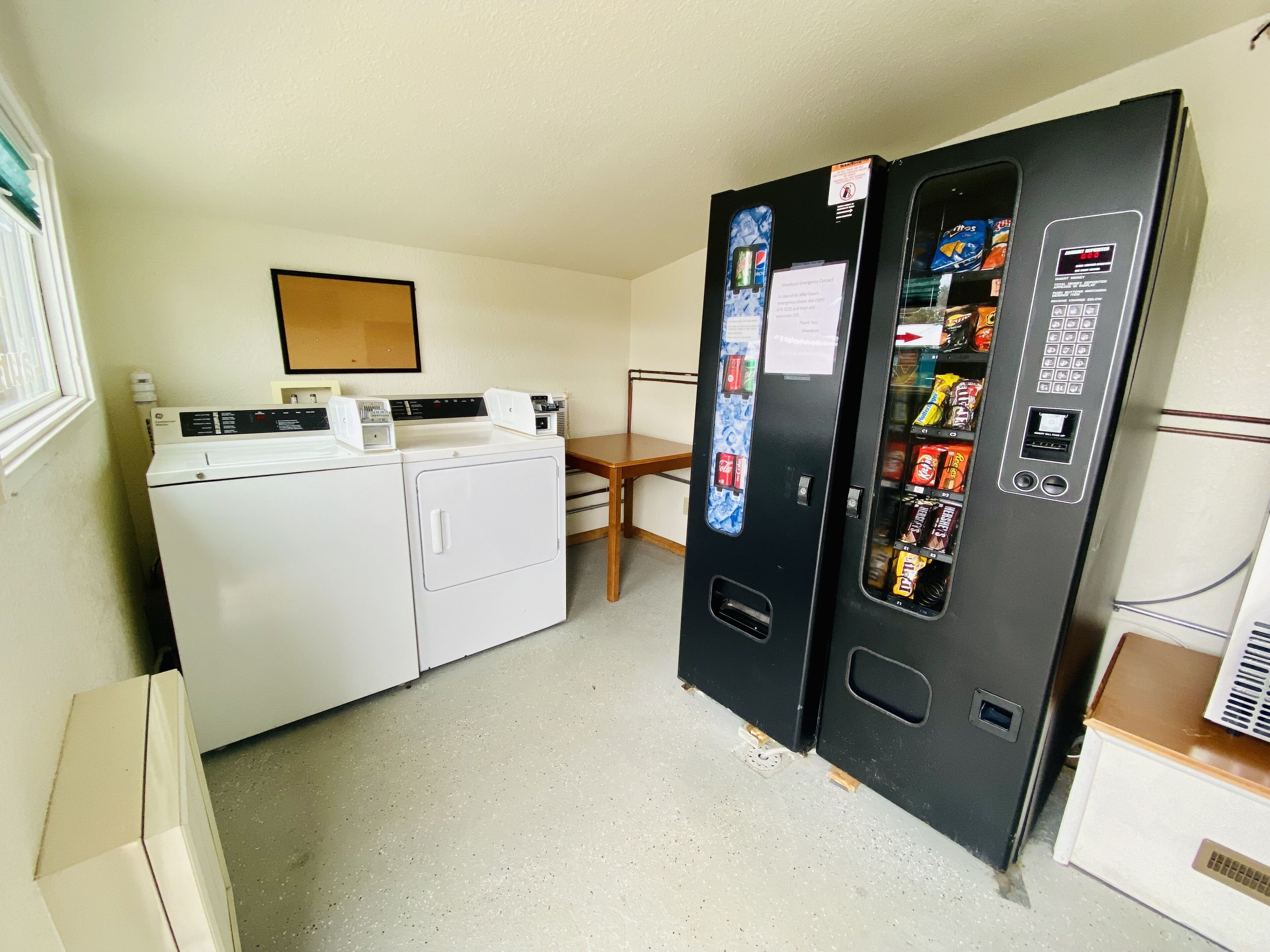 A laundry area with a washer and dryer, a vending machine, and a wooden chair.