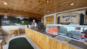 Een houten interieur met een receptiebalie, een muurschildering en een bord met de tekst 'Woody 444'.