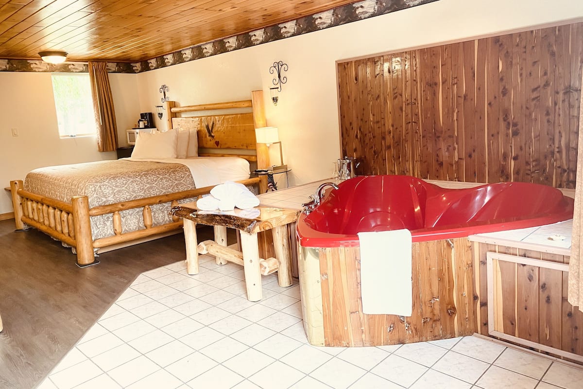 Une pièce de cabane en bois comprenant un lit, une baignoire rouge et une petite table.