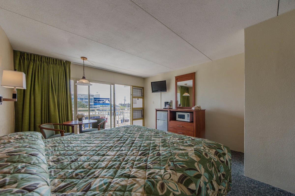 Quarto de hotel com uma cama grande, uma escrivaninha, televisão e vista para a cidade.