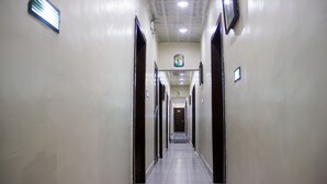 A long, narrow hallway with doors on both sides, leading to a central area with a sign above. - Benestar Suites (Lagos)