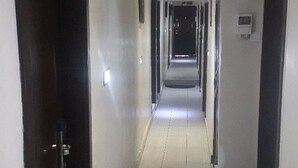 A long, narrow hallway with tiled floors and black-framed doors on both sides. - Benestar Suites (Lagos)