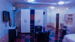 Una habitación de hotel con piso de cuadros, un armario, un escritorio y una cama.