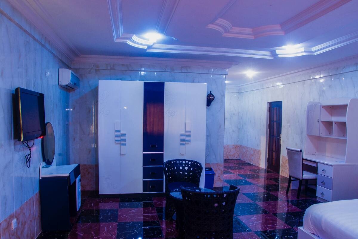 Una habitación de hotel con piso de cuadros, un armario, un escritorio y una cama.