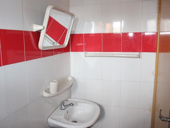 Un baño con un lavabo blanco, un espejo y una franja roja en la pared.