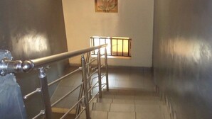 A staircase with metal railings leading to a landing. There is a window with a grid pattern and a framed picture on the wall. - Banilux Guest House (Lagos)