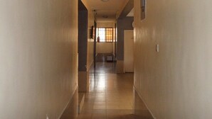 A long, narrow hallway with tiled floors and plain walls. - Banilux Guest House (Lagos)