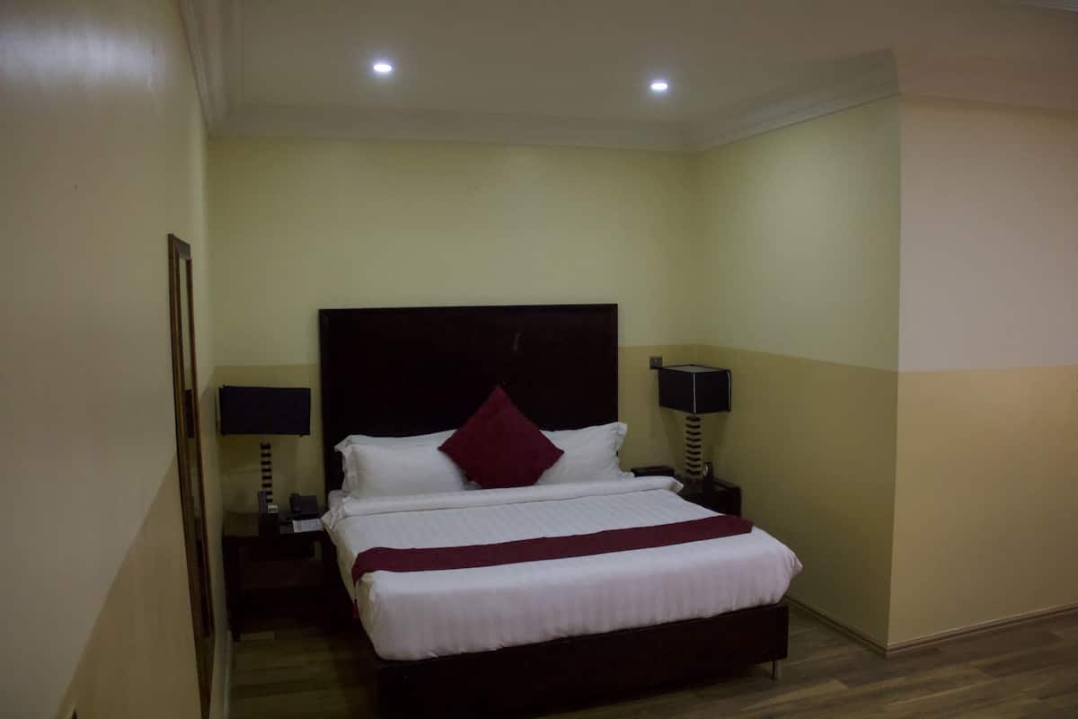 A hotel room with a bed, nightstands, and lamps.