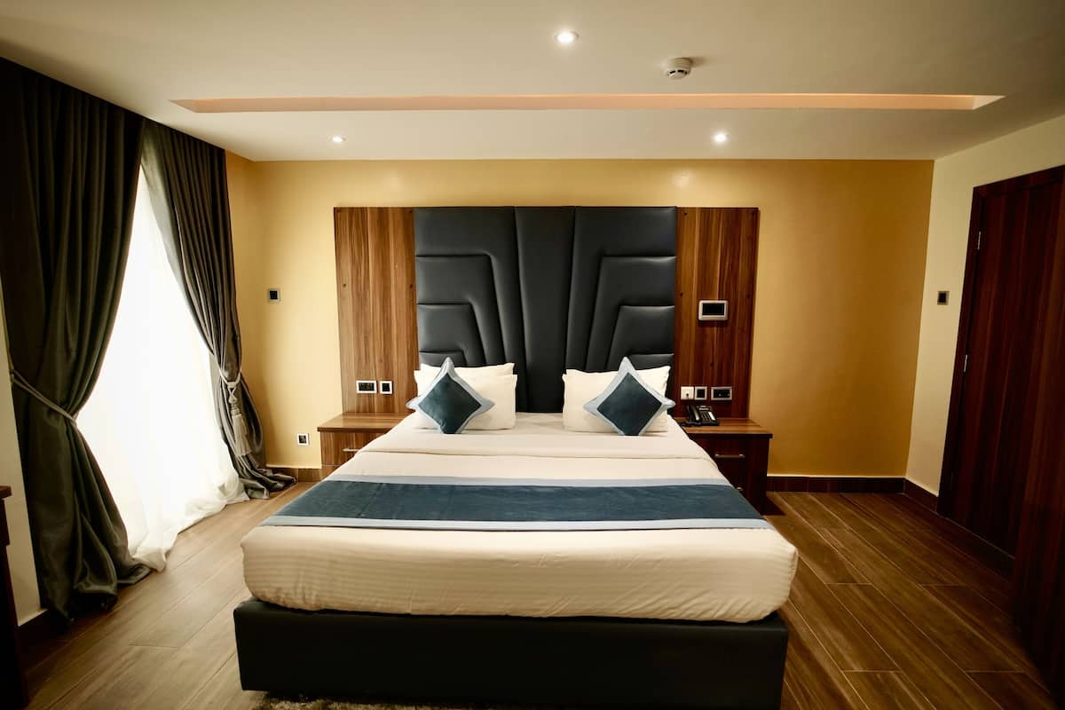 Quarto moderno com uma cama grande, cabeceira de madeira e um guarda-roupa.