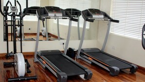 Une salle de sport équipée de tapis de course, d’un vélo d’appartement et d’un appareil d’aviron.