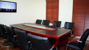 Une salle de conférence dotée d’une grande table rectangulaire, de chaises en cuir noir et d’un écran de télévision affichant le logo de « Watercress Hotels ».