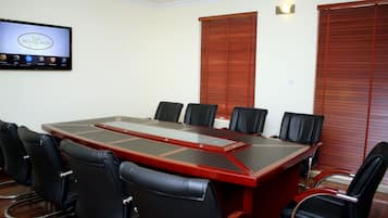 A conference room with a large rectangular table, black leather chairs, and a television screen displaying 'Watercress Hotels'.