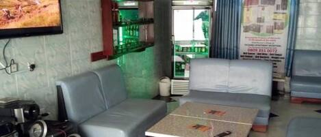 A room with a television, a bar area with shelves, a refrigerator, and a poster on the wall.