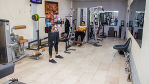 A gym with various exercise equipment, a television on the wall, and a mirror reflecting the equipment. - Pelican Hotel Lekki (Lekki)