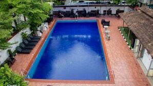 A rectangular swimming pool with a tiled deck, surrounded by lounge chairs and a covered seating area. - Pelican Hotel Lekki (Lekki)