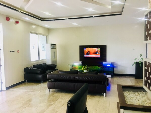 Una sala de estar moderna con televisor de pantalla plana, sofás de cuero, una mesa de centro y una planta decorativa.