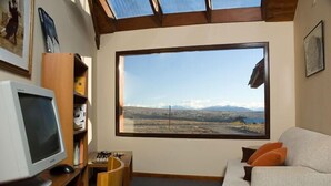 A room with a large window, a desk with a computer, a chair, and a sofa. - Hosteria Roble Sur (El Calafate)
