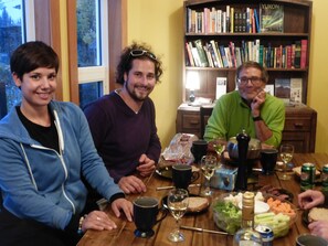 A dining table with food, drinks, and a bookshelf in the background. - Wanderer's Inn Backpackers Hostel (Haines Junction)