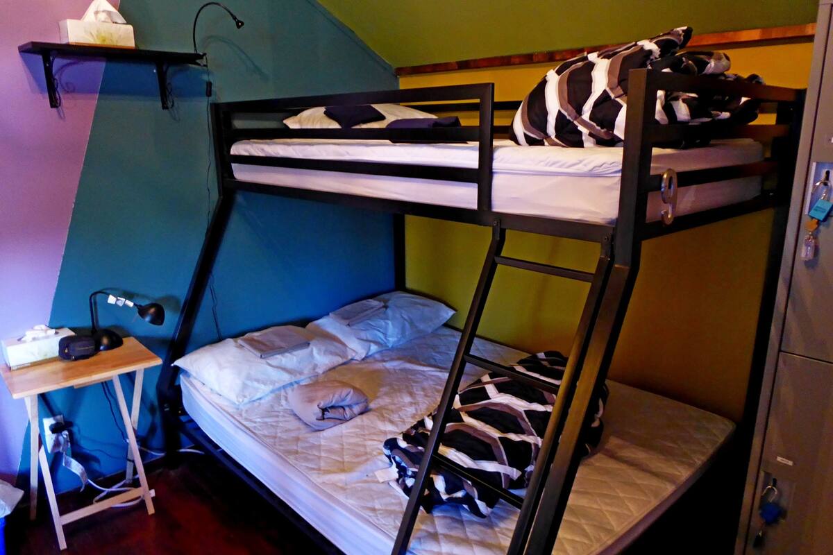 A bunk bed with a desk and chair, a shelf with a tissue box, and a lamp.