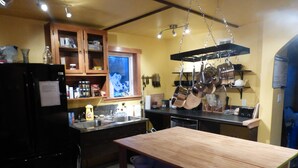 Una cocina con armarios de madera, un refrigerador negro y ollas colgadas.