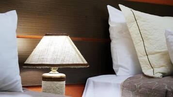 A bed with white bedding, a textured lamp on a wooden nightstand, and a dark wooden headboard.