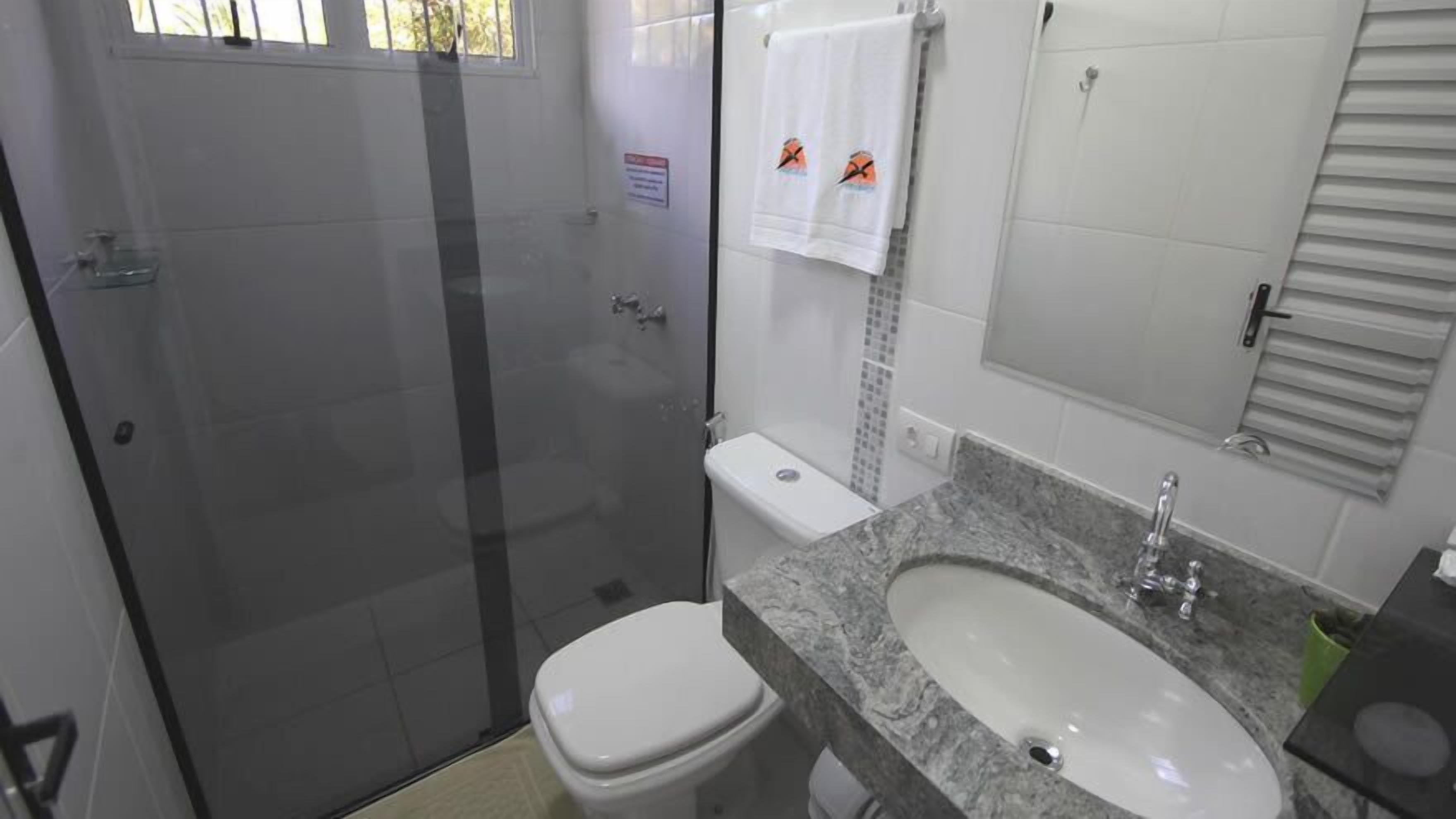 Une salle de bain équipée d’une douche, de toilettes, d’un lavabo et d’un miroir.