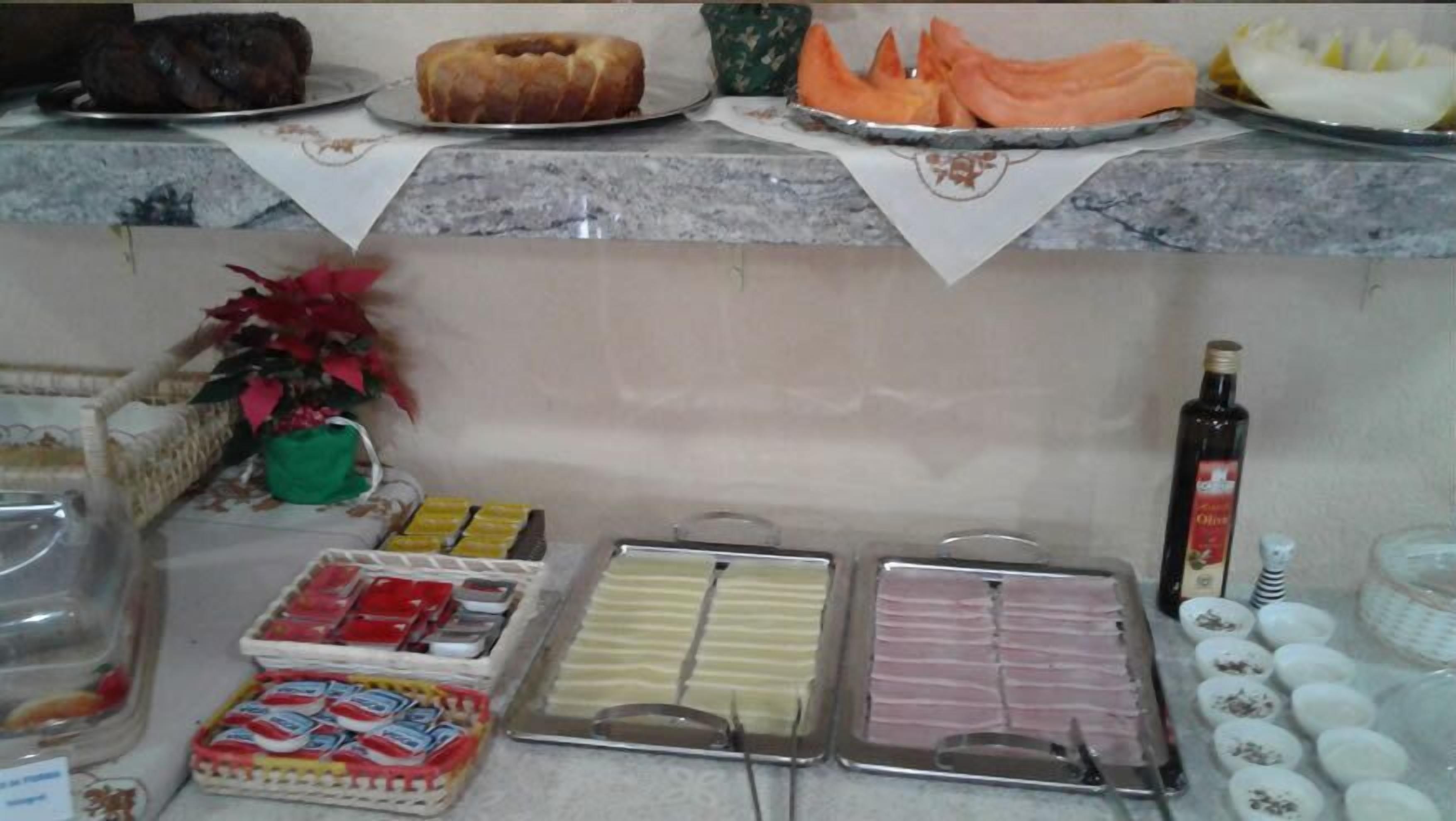 Un bufé con diversas opciones de comida, incluyendo un pastel, pastelería y fiambres.