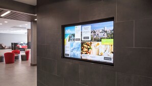 A digital display in a lobby with various advertisements for local attractions and dining options.