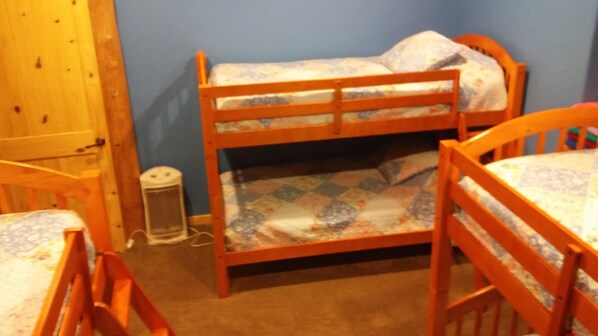 A bunk bed room with a wooden floor, a small table, and a chair. - Teton Hostel HideAway (Driggs)