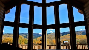 Habitación con amplias ventanas que ofrecen vistas a colinas otoñales y un cielo despejado.