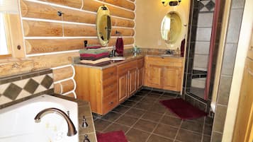 A bathroom with wooden cabinetry, a sink with a vanity, two mirrors, and a shower area.