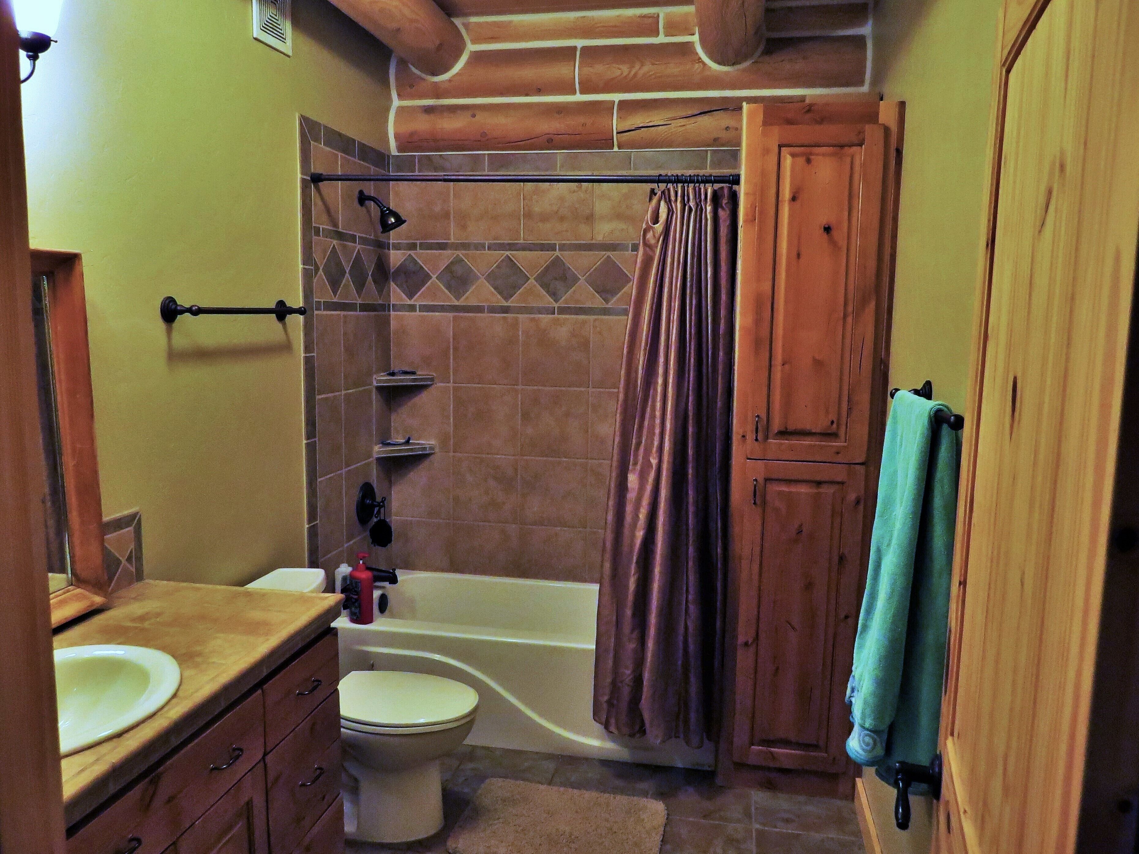 Ein Badezimmer mit Badewanne, Toilette, Waschtisch und Holzschränken.