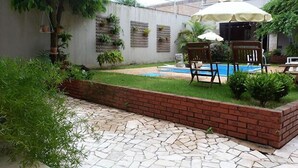 Un jardin avec une piscine, un parterre en briques et du mobilier d’extérieur.