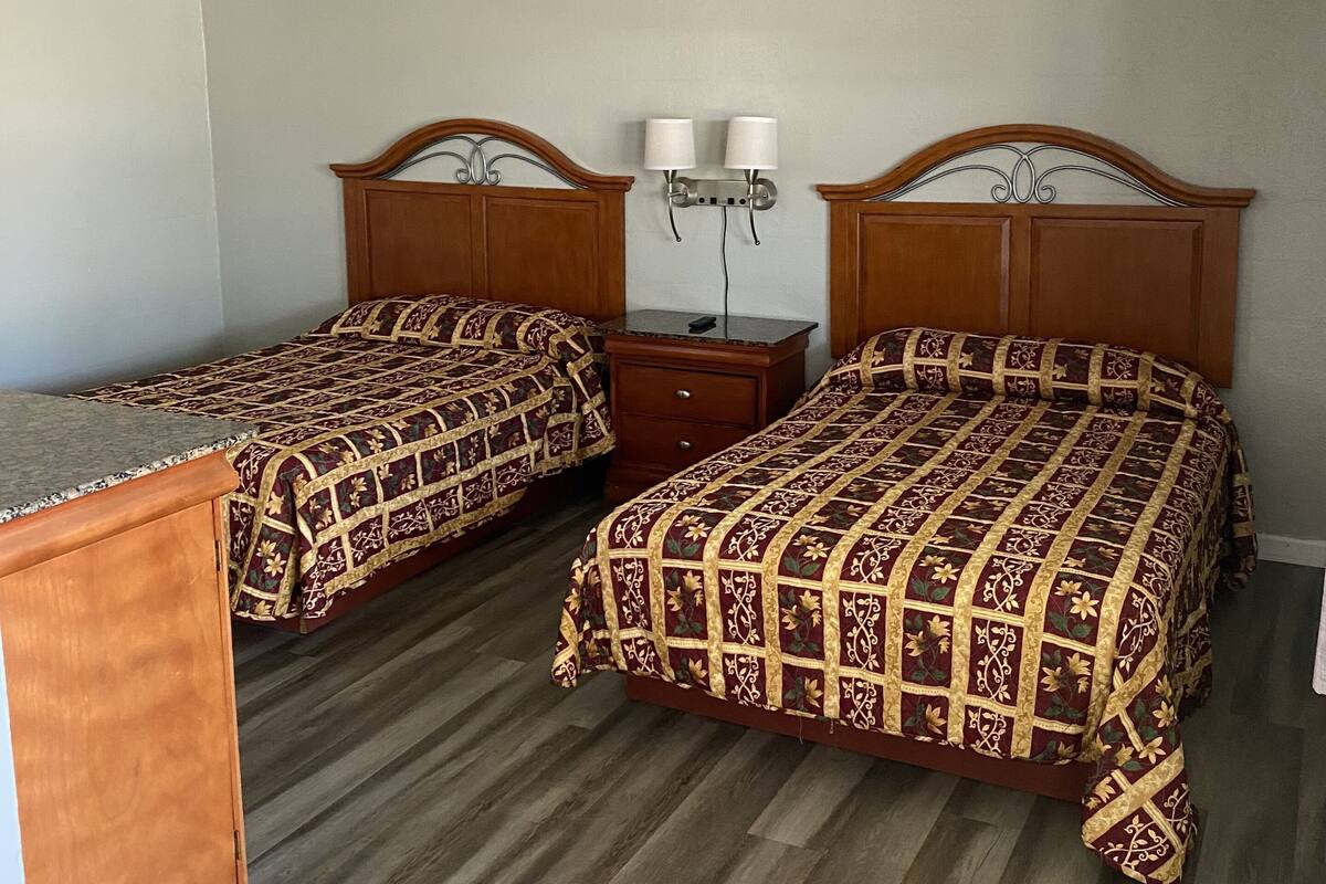 Ein Zimmer mit zwei Betten, einem Nachttisch und einer Kommode.