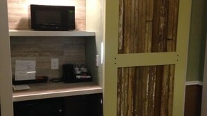 Una cocina compacta equipada con microondas, cafetera y un refrigerador pequeño.