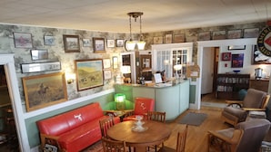 Una habitación acogedora con un sofá rojo, una mesa de comedor de madera y sillas, una zona de bar con mostrador y una estantería llena de libros.