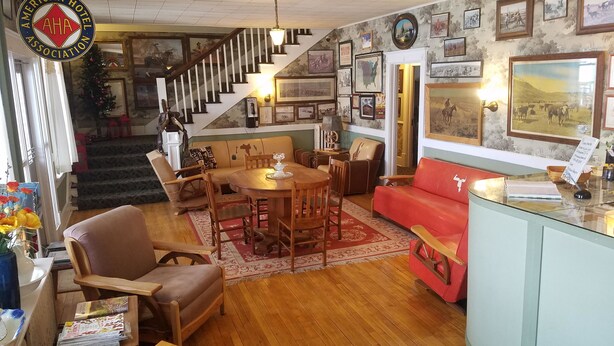 Amplia sala de estar con piso de madera, un sofá rojo, una mesa de comedor con sillas y una escalera que lleva a otro nivel.