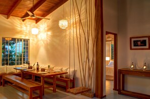 A dining area with wooden tables and benches, a ceiling fan, and a view of the outdoors. - Moana Surf Resort (Nosara)