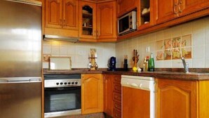 Una cocina con armarios de madera, un refrigerador de acero inoxidable, un microondas, una estufa y un lavavajillas.
