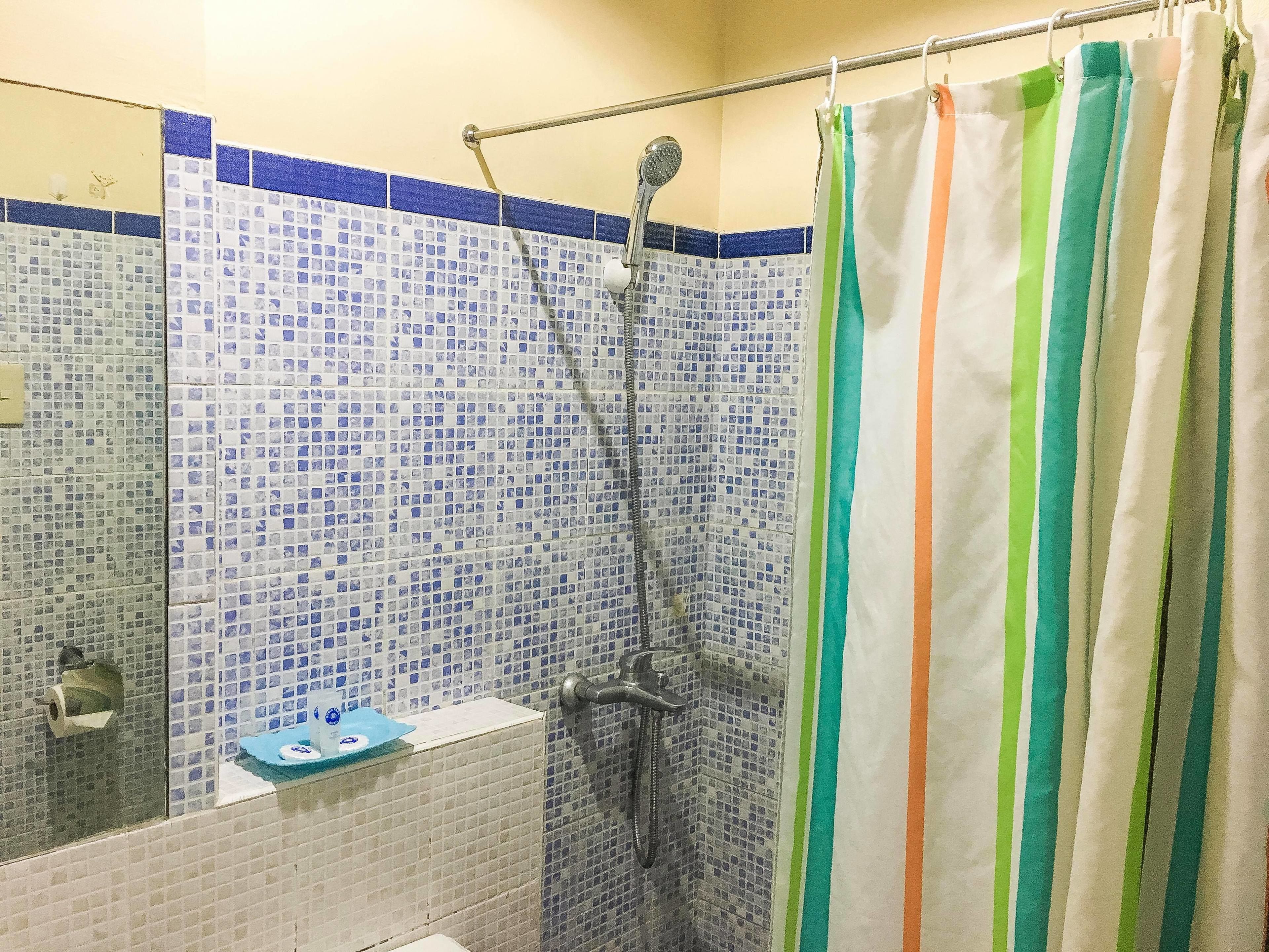 A bathroom with a shower, tiled walls, and a striped shower curtain.