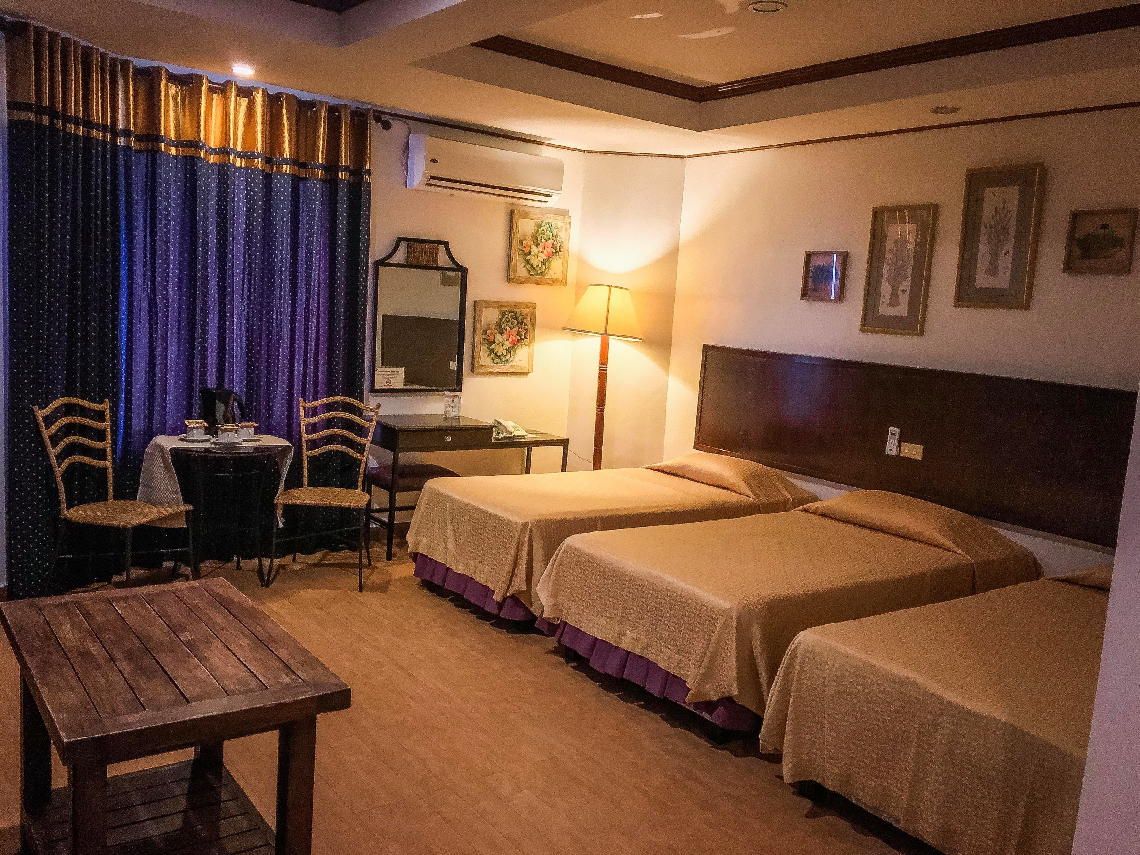 Una habitación de hotel con dos camas, un escritorio, una silla, una mesa y una lámpara.