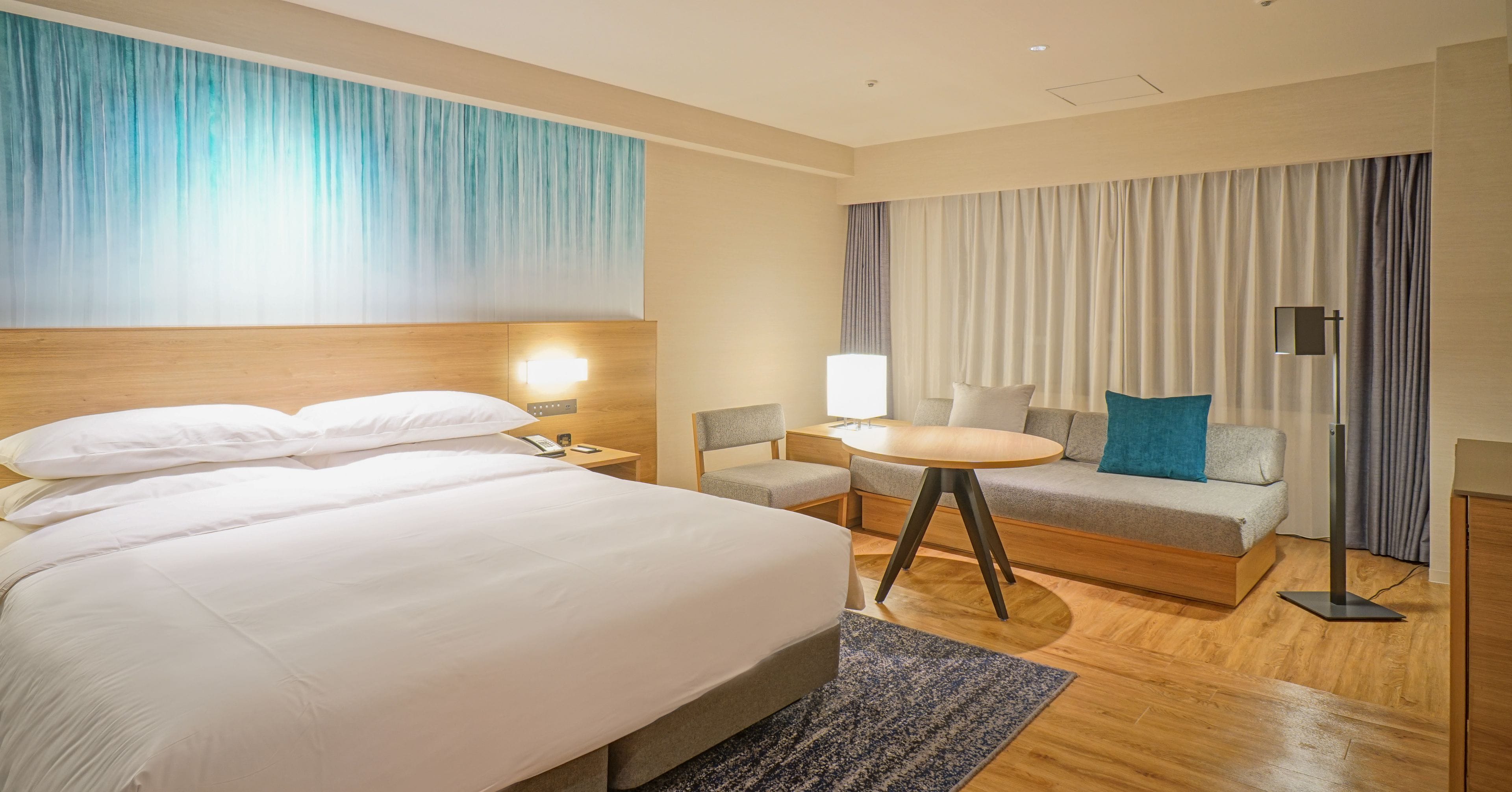 Una habitación de hotel con una cama grande, un escritorio, un sofá y una lámpara.