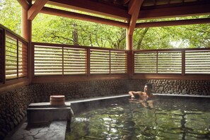 A traditional Japanese onsen with stone walls, wooden beams, and a view of lush greenery. - Fuji Marriott Hotel Lake Yamanaka (Yamanakako)