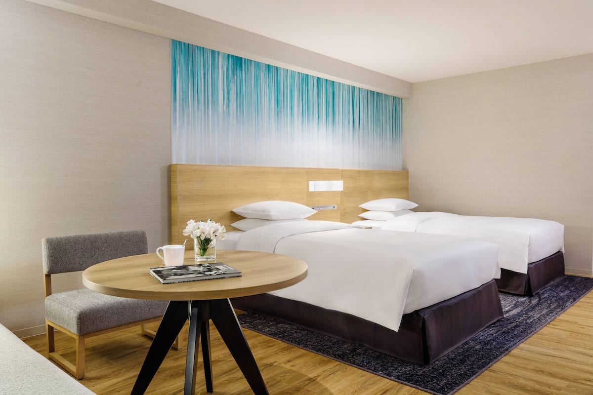 Habitación de hotel con cama, mesita de noche con lámpara, una silla y una pared con diseño degradado en azul.