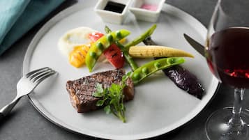A plate with a steak, vegetables, and a glass of red wine.