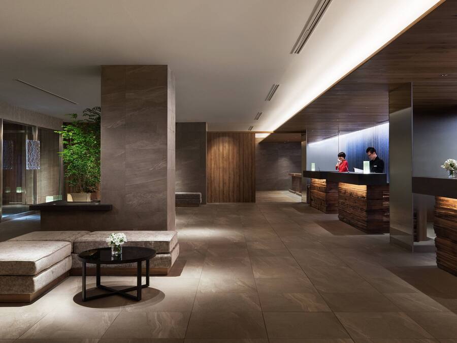 A modern lobby with a reception desk, seating area, and a large plant.
