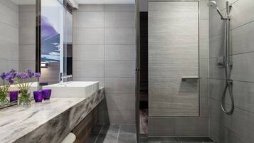A modern bathroom with a large mirror, a marble countertop, and a shower area.